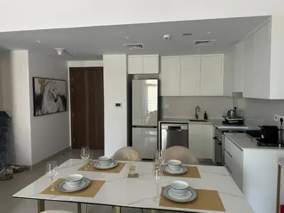 a kitchen with a table with plates and glasses on it at Brand new apartment next to Burj Al Arb in Dubai