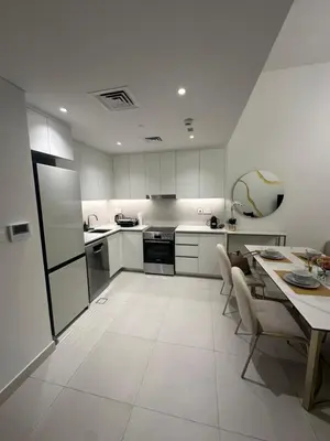 a kitchen with white cabinets and a table with chairs at Brand new apartment next to Burj Al Arb in Dubai