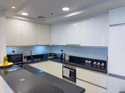 a kitchen with white cabinets and black counter tops at Modern and Spacious 2BR in Business Bay in Dubai