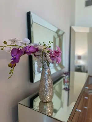 a vase with flowers on a glass table in front of a mirror at Modern and Spacious 2BR in Business Bay in Dubai
