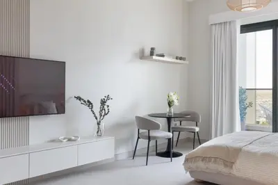 a bedroom with a tv and a table with chairs at Brand New Luxury Stays by Edora at Sway Residence Dubai Hills in Dubai