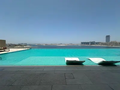 a swimming pool with two lounge chairs on a building at Golden Coast Stay in Dubai