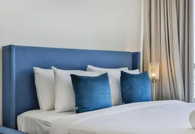 a blue and white bed with blue and white pillows at Carson Tower B,Damac Hills - Studio Apartment - Allsopp & Allsopp in Dubai