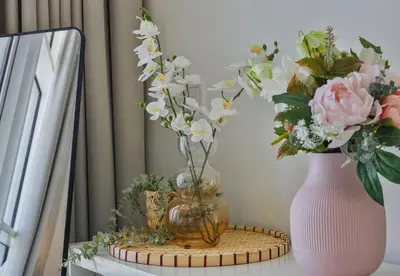 a vase with flowers on a table next to a mirror at Carson Tower B,Damac Hills - Studio Apartment - Allsopp & Allsopp in Dubai