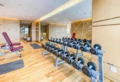 a gym with a row of dumbbells and a chair at Carson Tower B,Damac Hills - Studio Apartment - Allsopp & Allsopp in Dubai