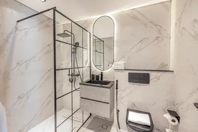 a bathroom with a shower with a sink and a mirror at Daniels 3BR with Palm View at Marina Pinnacle in Dubai
