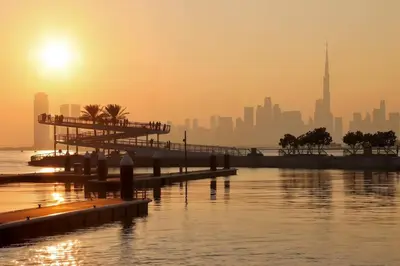 a city skyline at sunset with a pier and the water at Livbnb-Elegant 2BR, Creek Beach, Pool & Gym in Dubai
