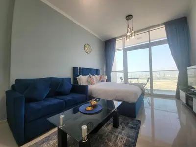 a living room with a bed and a blue couch at DVR Studio apartment available in Damac Hills in Dubai