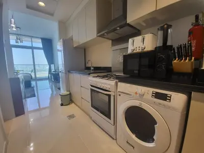 a kitchen with a washing machine and a microwave at DVR Studio apartment available in Damac Hills in Dubai