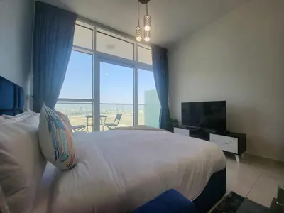 a bedroom with a large bed and a large window at DVR Studio apartment available in Damac Hills in Dubai