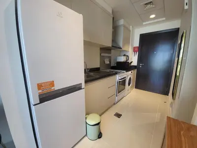 a small kitchen with a refrigerator and a stove at DVR Studio apartment available in Damac Hills in Dubai