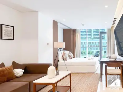 a living room with a couch and a table at Luxury at Sterling East Studio with Park Views in Dubai