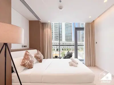 a bedroom with a white bed and a large window at Luxury at Sterling East Studio with Park Views in Dubai