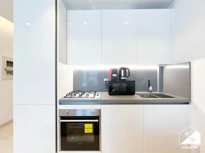 a kitchen with white cabinets and a stove top oven at Luxury at Sterling East Studio with Park Views in Dubai