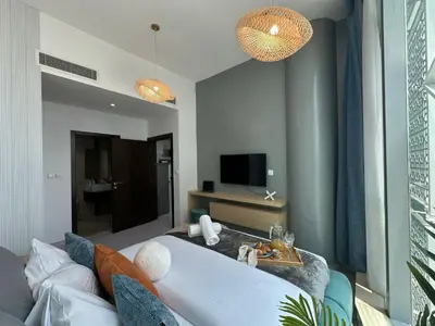 a living room with a couch and a tv at Sunsets and Skylines 1BR in Panoramic Tower in Dubai