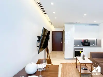 a living room with a couch and a kitchen at Streling Studio with Balcony & City Views in Dubai
