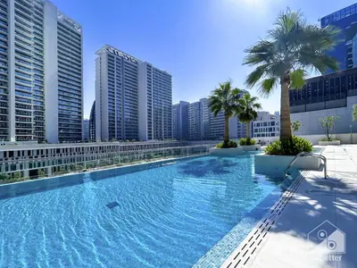 a large swimming pool with palm trees and buildings at Streling Studio with Balcony & City Views in Dubai