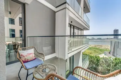 a balcony with two chairs and a table and a window at Waves - Rustic Chic 1 BR Retreat in Vibrant JVC in Dubai
