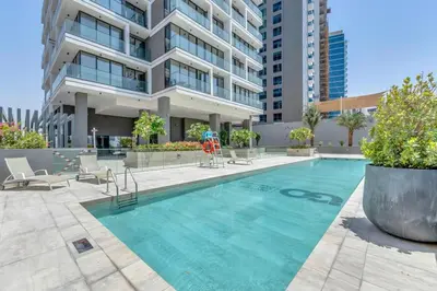 a swimming pool in front of a building at Waves - Rustic Chic 1 BR Retreat in Vibrant JVC in Dubai
