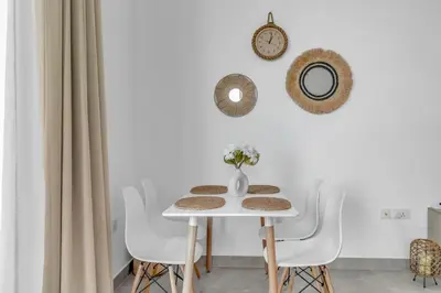 a white dining room with a white table and chairs at Waves - Rustic Chic 1 BR Retreat in Vibrant JVC in Dubai
