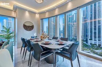 a dining room with a table and chairs and large windows at bnbme - Luxury Downtown Dubai Apt Burj Khalifa Fountain Views Pool Gym Parking in Dubai