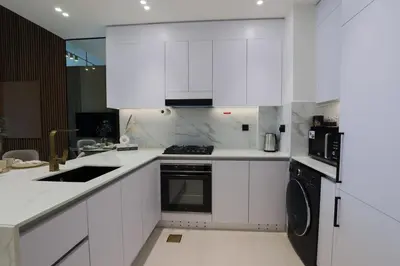 a white kitchen with white cabinets and a dishwasher at Gracious 1BR in Binghatti Amber in Dubai