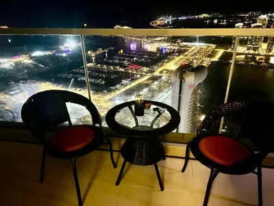 three chairs and a table on a balcony at night at Ocean Heights Dubai Marina Ocean View in Dubai