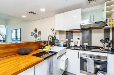 a kitchen with white cabinets and a wooden counter top at Ocean Heights Dubai Marina Ocean View in Dubai