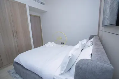 a bedroom with a white bed and a couch at Standard 1BHK located in Azizi Riviera 48 in Dubai