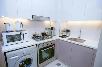 a kitchen with a washing machine and a microwave at Standard 1BHK located in Azizi Riviera 48 in Dubai