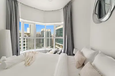 a bedroom with a white bed and a large window at Bright Studio in Dubai Gate 2 in Dubai