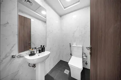 a white bathroom with a sink and a toilet at Stylish 1BR with large Terrace JVC in Dubai