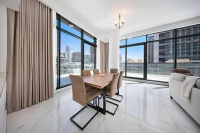 a dining room with a table and large windows at Stylish 1BR with large Terrace JVC in Dubai