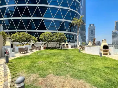 a park in front of a building with a grass field at Vogue DIFC Damac Park Tower near Museum of The Future, One Bedroom Apartment with Balcony, City Skyline and Museum of The Future View, Access to all Amenities in Dubai