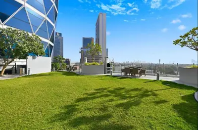 a grassy area in a city with a building at Vogue DIFC Damac Park Tower near Museum of The Future, One Bedroom Apartment with Balcony, City Skyline and Museum of The Future View, Access to all Amenities in Dubai