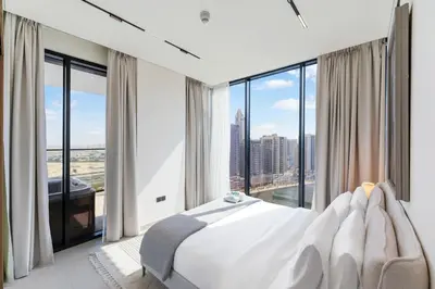 a bedroom with a white bed and large windows at FAM Living Trillionaire Residences Premium Studio with Private Jacuzzi and Canal View in Dubai