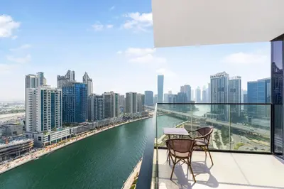 two chairs and a table on a balcony overlooking a river at FAM Living Trillionaire Residences Premium Studio with Private Jacuzzi and Canal View in Dubai