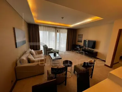 a living room with a couch and chairs and a tv at Kempinski Central Avenue One Bedroom in Dubai