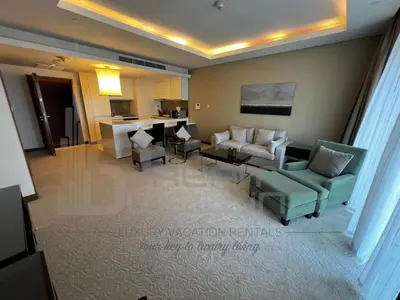a living room with a couch and chairs and a kitchen at Kempinski Central Avenue One Bedroom in Dubai