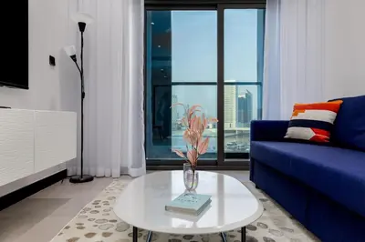 a living room with a blue couch and a table at Waves - Premium 1BR Apartment Overlooking Burj Khalifa in Dubai