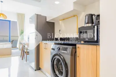 a kitchen and living room with a washing machine at Bloomfields Cozy Stu in Alexis Tower in Dubai