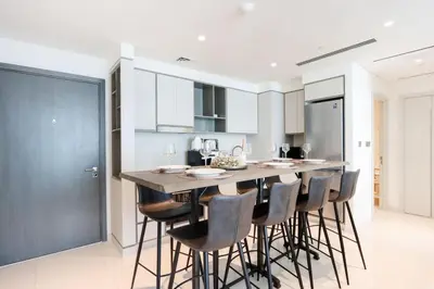 a kitchen with a large wooden bar with stools at Livbnb - Chic 1BR, Beachfront & Marina Views in Dubai