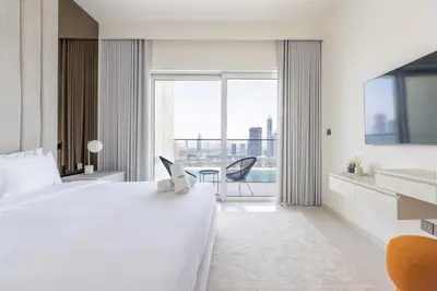 a hotel room with a bed and a desk with a laptop at Designer 2-BR - Sea View - Grand Bleu by Elie Saab in Dubai
