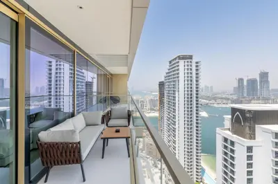 an apartment balcony with a couch and a view of the city at Designer 2-BR - Sea View - Grand Bleu by Elie Saab in Dubai