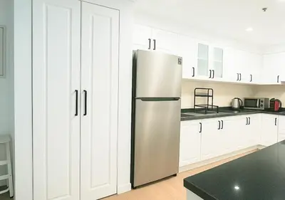 a kitchen with white cabinets and a stainless steel refrigerator at DreamShoma- Super Spacious 1BR Lake View in Dubai