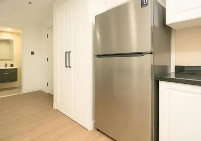 a stainless steel refrigerator in a kitchen with white cabinets at DreamShoma- Super Spacious 1BR Lake View in Dubai