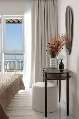 a bedroom with a bed and a table with flowers on it at Palm-View 2BR Elie Saab Luxury in Dubai