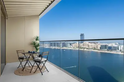 a balcony with a table and chairs and a view of the water at Palm-View 2BR Elie Saab Luxury in Dubai