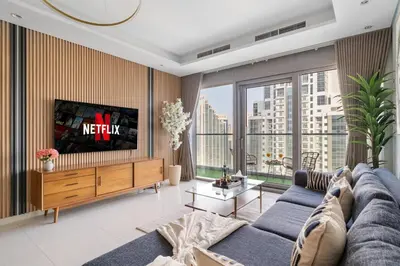 a living room with a couch and a tv at Sky-High Infinity Pool with Burj Khalifa Views in Dubai