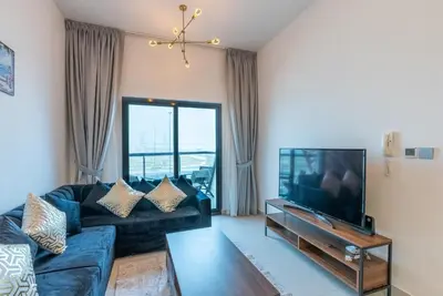 a living room with a couch and a tv at 1 Bedroom in JVC in Dubai